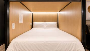 A compact bed with a wooden headboard and a simple, clean design.