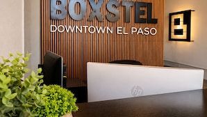 A reception desk with a sign reading 'BOXSTEEL DOWNTOWN EL PASO' and a modern interior design. - Boxstel - Moderns Stay Hotel (El Paso)