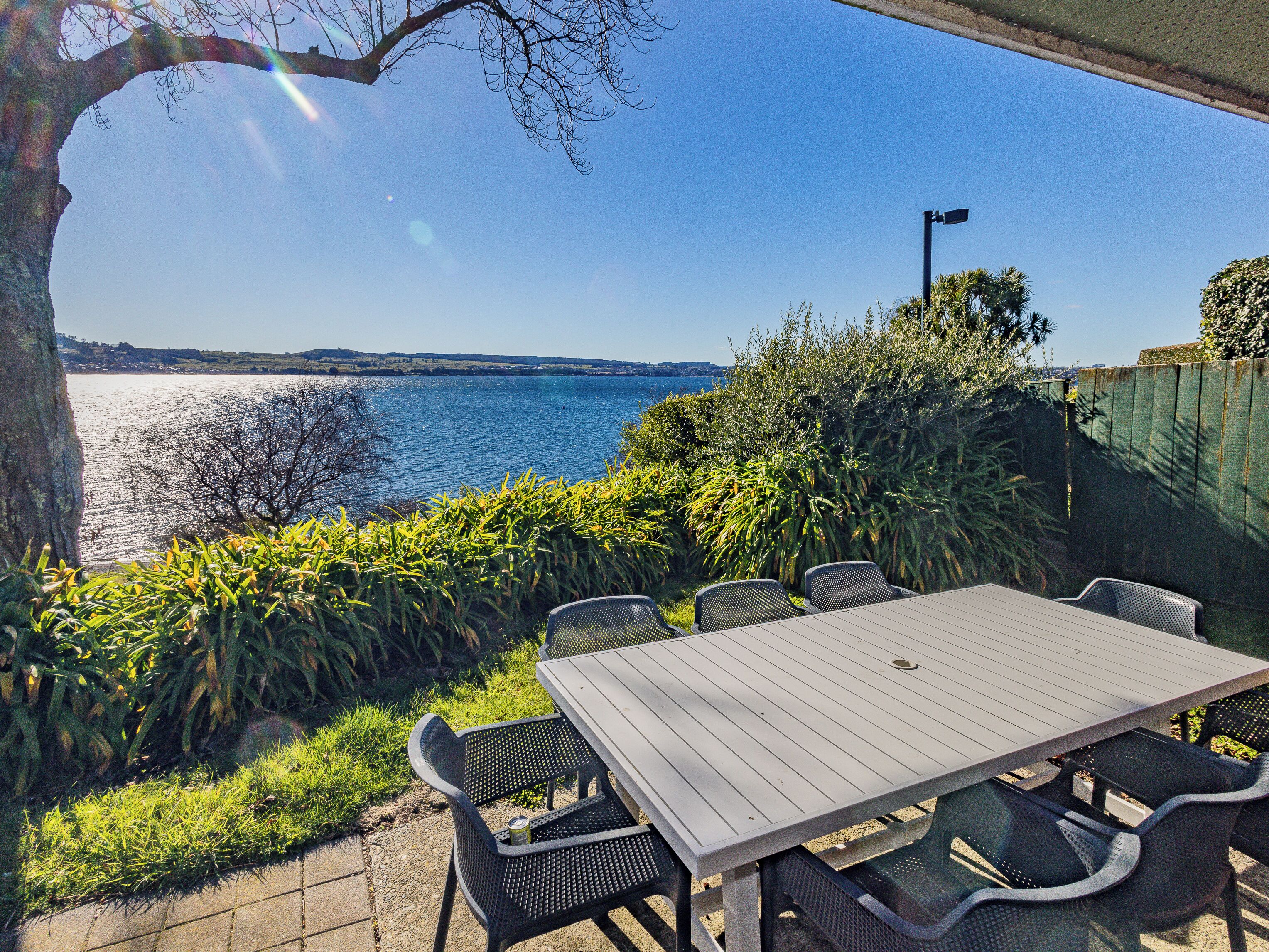 Un patio exterior con mesa y sillas con vista al agua.