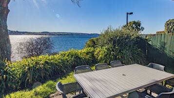 An outdoor patio with a table and chairs overlooking a body of water.