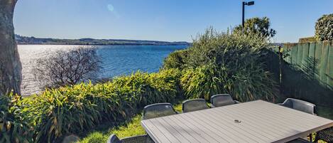 Un patio exterior con mesa y sillas con vista al agua.