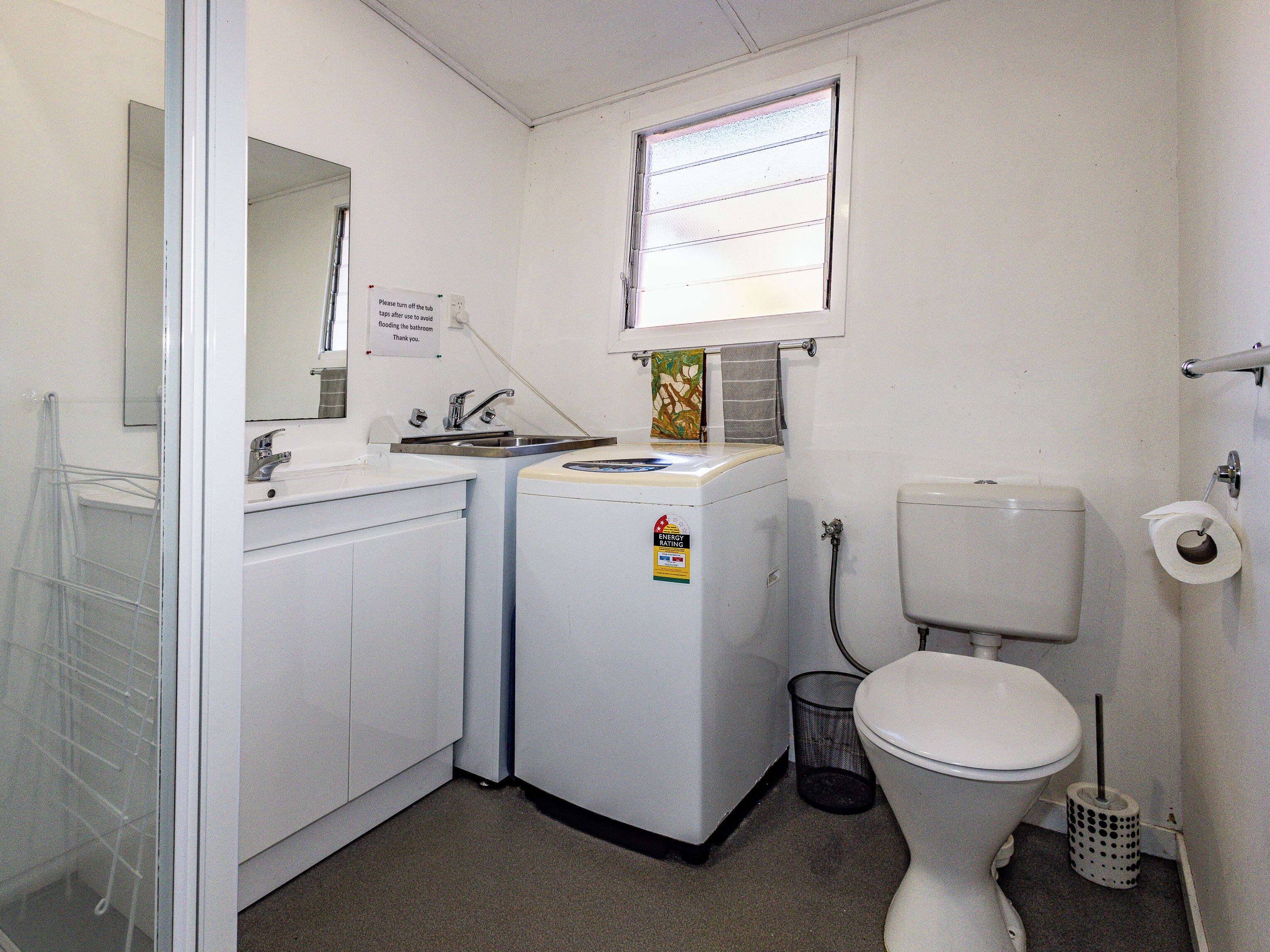 Un baño pequeño con lavamanos, espejo, inodoro y ventana.