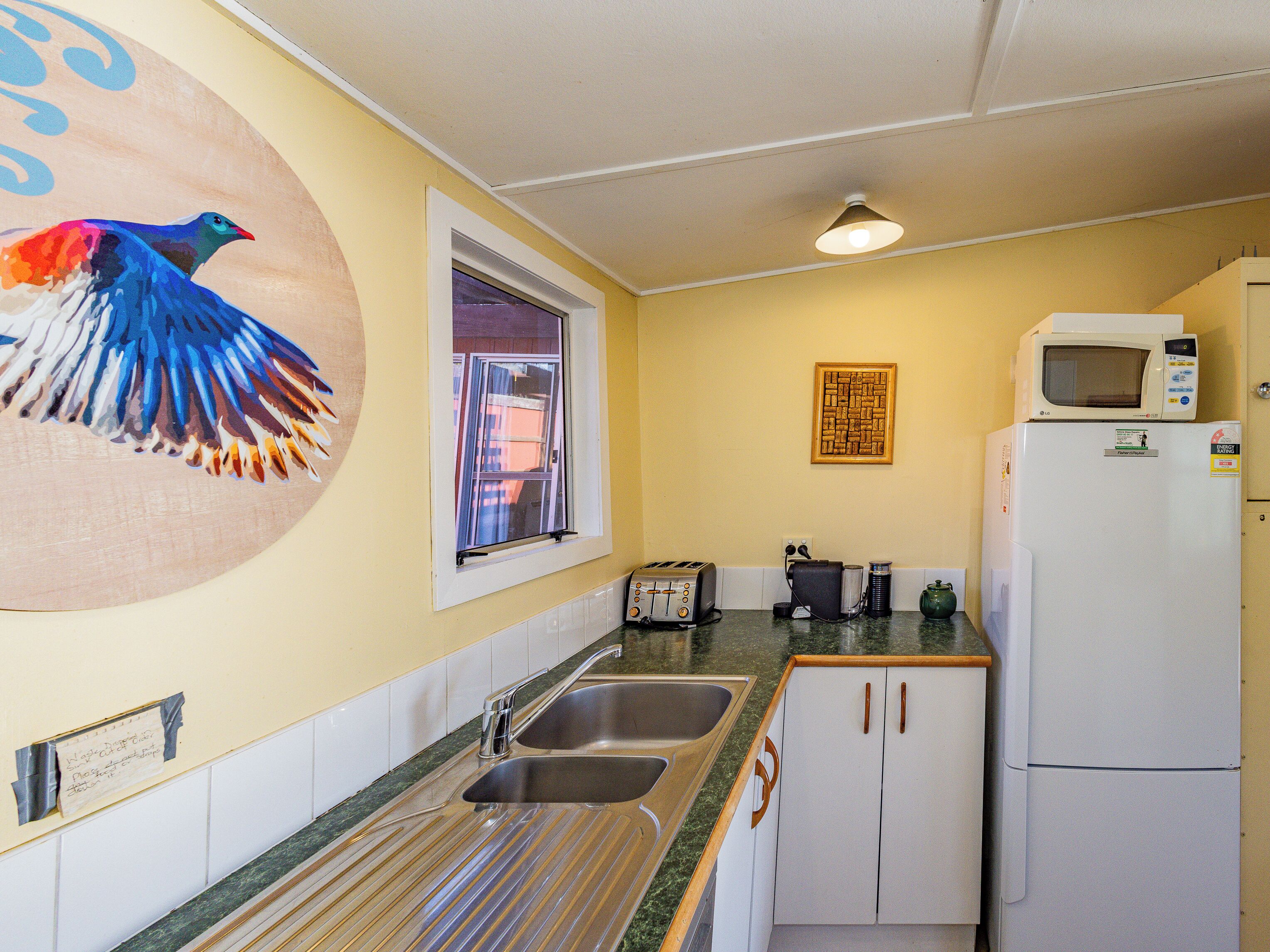 A kitchen with a double sink, a microwave, a toaster, and a refrigerator.