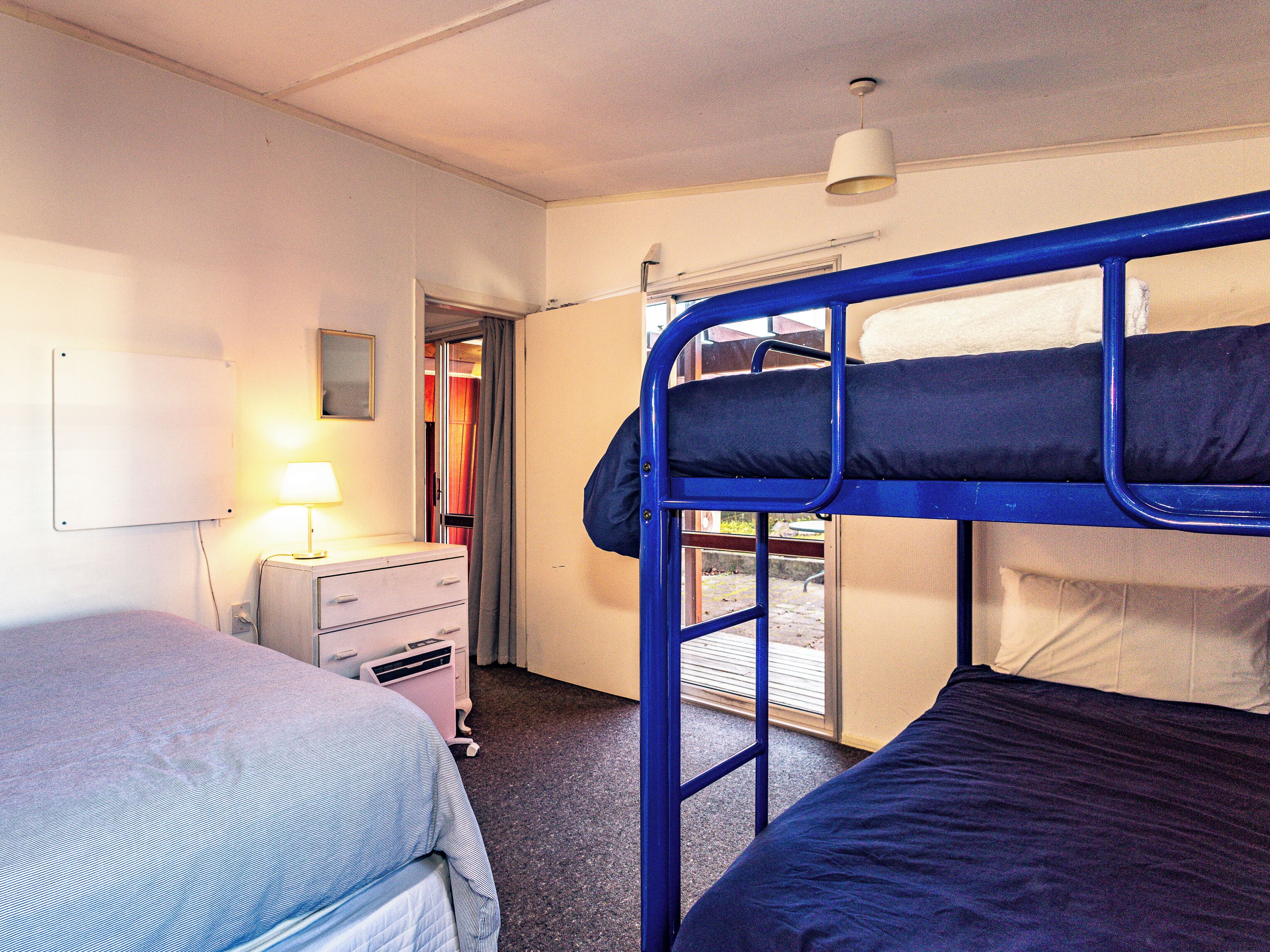 Ein Schlafsaalzimmer mit Etagenbetten, einem Schreibtisch mit Lampe und einem Fenster.