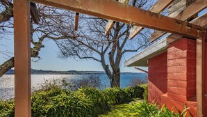 A covered outdoor area with a view of a body of water and distant hills. - Moeroa - Wharewaka Holiday Home (Wharewaka)