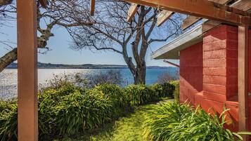 A covered outdoor area with a view of a body of water and distant hills.