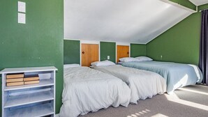 A room with two beds, a bookshelf, and a door. - Moeroa - Wharewaka Holiday Home (Wharewaka)