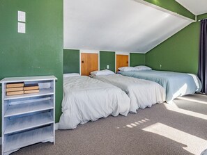 A room with two beds, a bookshelf, and a door. - Moeroa - Wharewaka Holiday Home (Wharewaka)