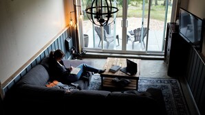 A room with a sofa, a coffee table, a TV, and a large window with a view of outdoor furniture. - Smith Lake Farm (Black Creek)