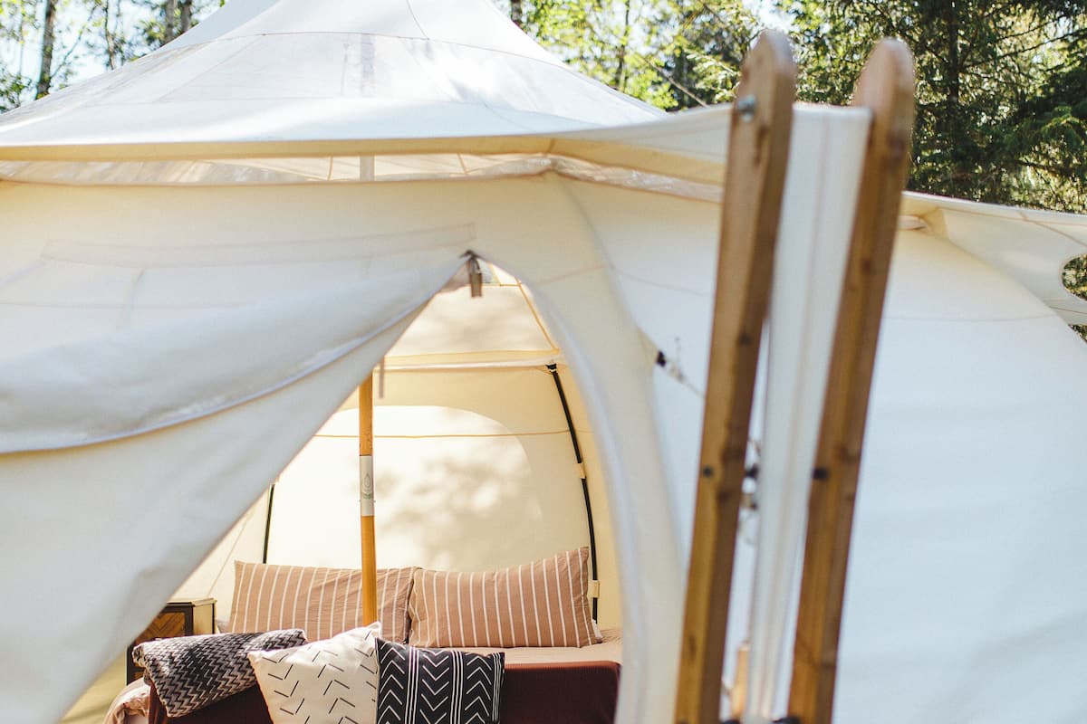 A tent with a bed inside, surrounded by trees.