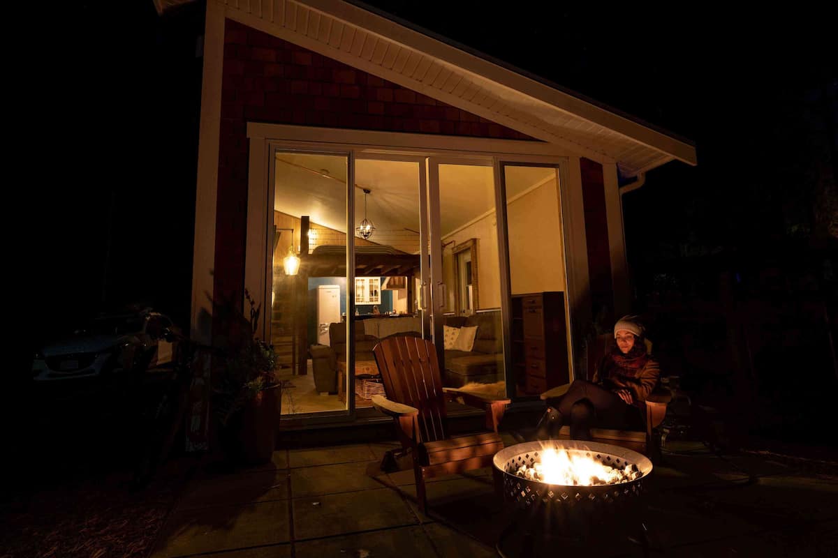 A house with a fire pit in the front yard, a sliding glass door entrance, and a visible kitchen area inside.