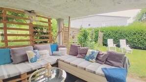 An outdoor seating area with a sofa, cushions, and a glass table.