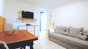 A living room with a sofa, a table, and a television mounted on the wall.