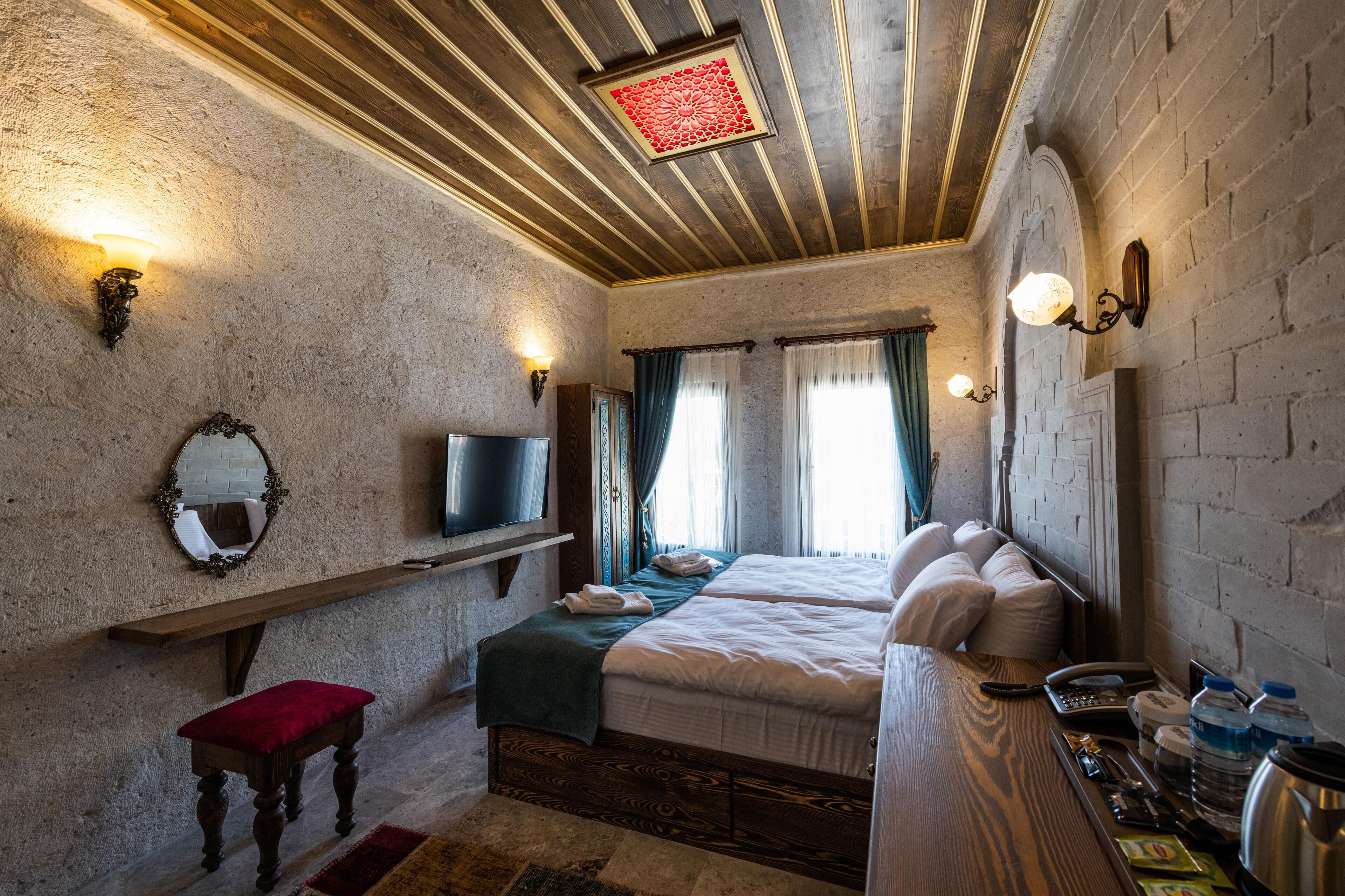 Une chambre avec un lit, une télévision, un banc et une table avec des articles de toilette.