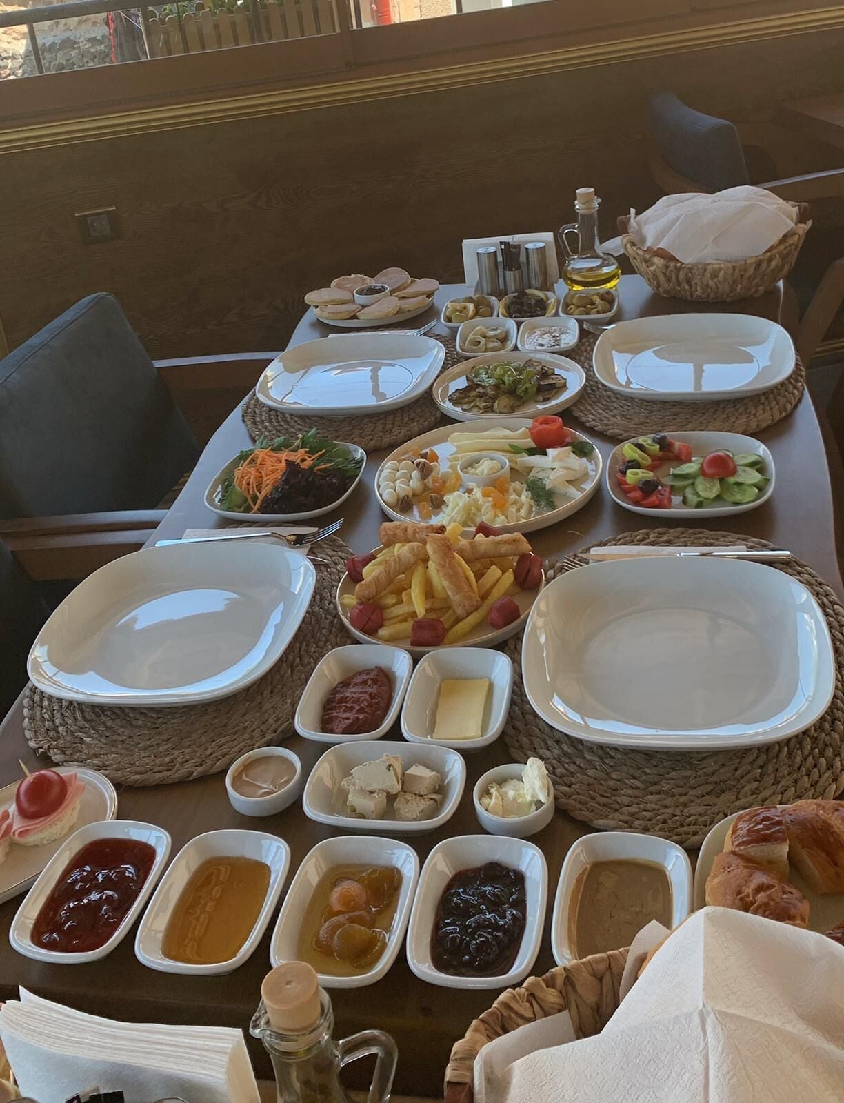 Une table dressée avec divers plats, notamment des salades, des viandes et des fromages, disposés sur des sets de table en fibres tressées.