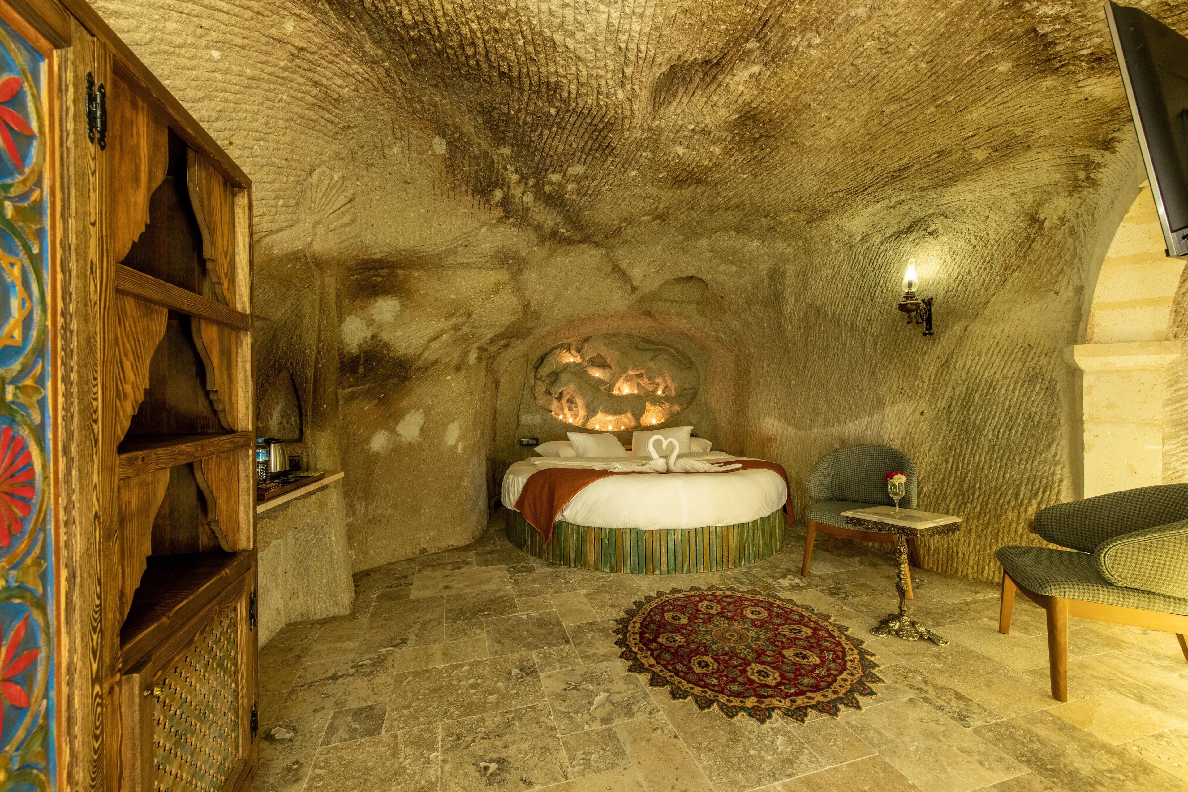 Une chambre confortable, à l’aspect de grotte, avec un lit, une petite table et une chaise.