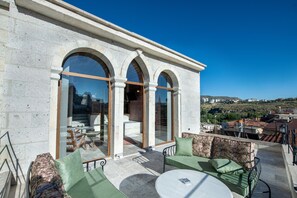 Eine Dachterrasse mit Steinverkleidung, großen Bogenfenstern und Außenbestuhlung.