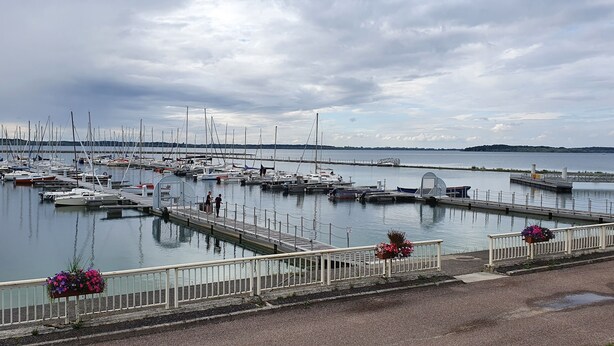 A marina with multiple boats docked, a pedestrian bridge, and a calm water body.