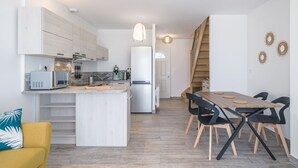 A modern kitchen with white cabinets, a central island, and a dining area with a wooden table and black chairs.