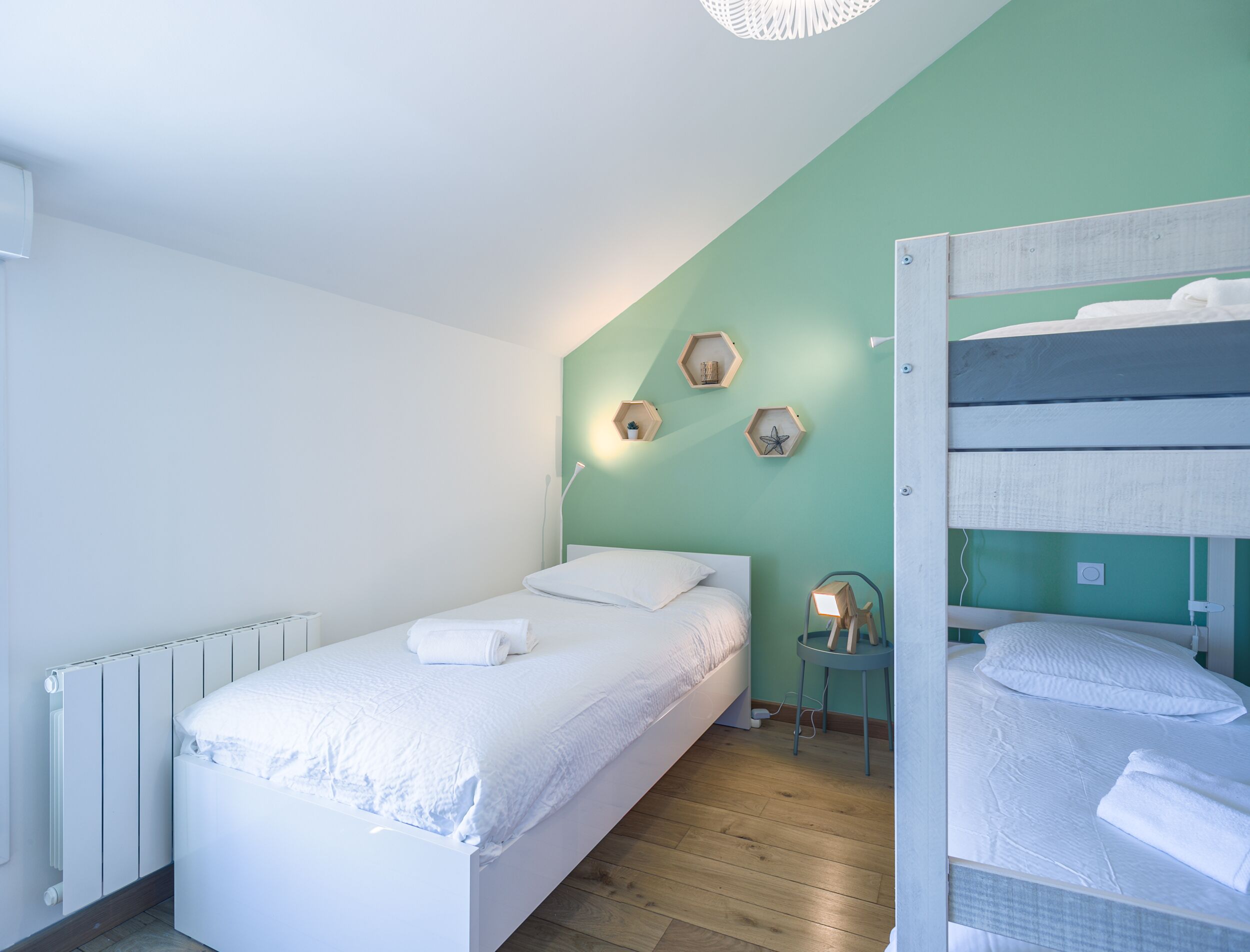 Ein Schlafzimmer mit einem Einzelbett, einem Etagenbett, einem Heizkörper und sechseckigen Wandverzierungen.