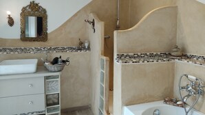 Un baño con una bañera independiente, ducha, lavamanos con espejo y un adorno de pared.