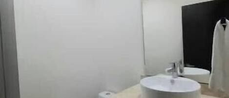 A modern bathroom with a toilet, sink, and mirror.