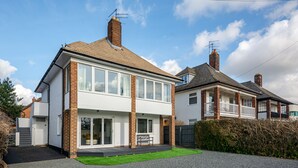 A modern two-story house with a large front window, a balcony, and a well-maintained lawn. - Luxury 2 Bedroom Apartment in Kettering (Kettering)