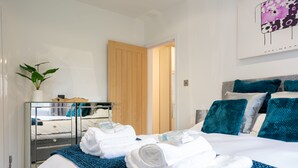 A hotel room with a bed, a mirror, a plant, and a painting on the wall. - Luxury 2 Bedroom Apartment in Kettering (Kettering)