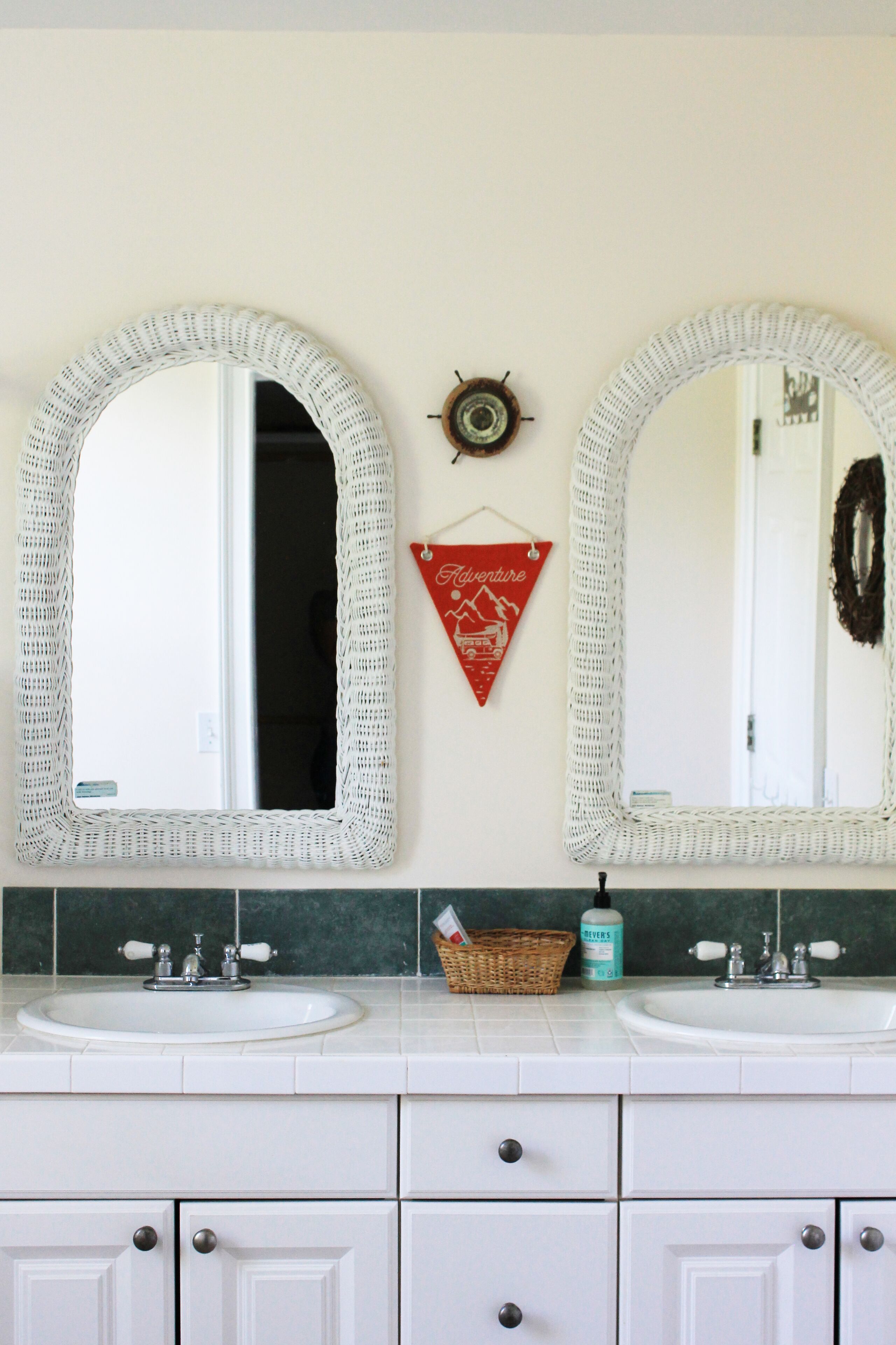 Une salle de bain avec deux grands miroirs, un lavabo et un meuble.