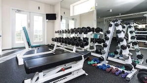 Une salle de sport équipée de matériel de musculation, de bancs et d’haltères.