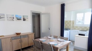 Una cucina compatta con zona pranzo, mobili in legno e vista all'esterno da una finestra.