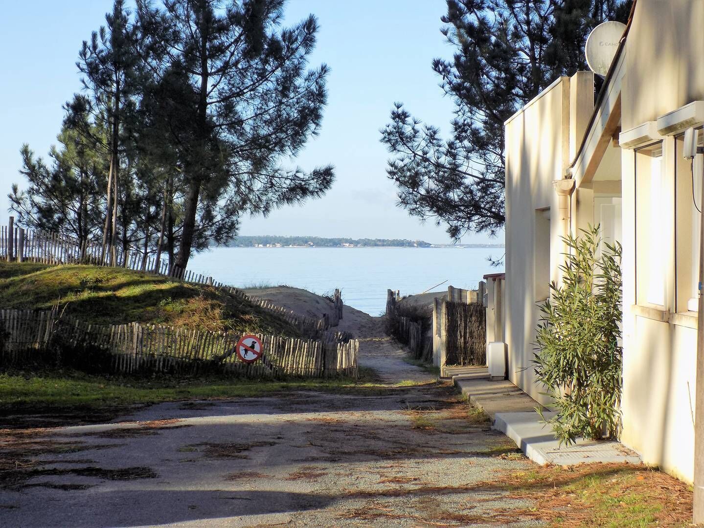 Une route étroite menant à un bâtiment d’où l’on a une vue sur la mer.
