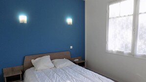 Una camera da letto con un letto, due lampade a parete, una finestra e un comodino.