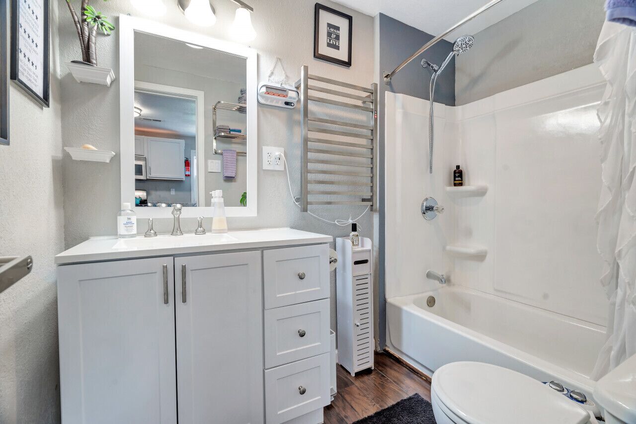 A modern bathroom with a white vanity, a large mirror, a shower, and a toilet.