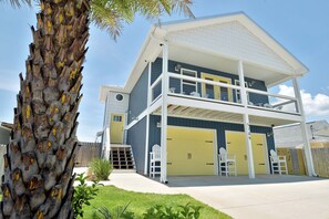 A two-story house with a covered porch, a garage, and a small outdoor seating area. - PCB oasis, stunning private saltwater pool, 6 min walk to the beach. (Panama City Beach)