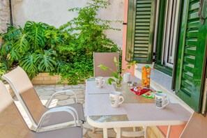 An outdoor seating area with a table, chairs, and a potted plant.