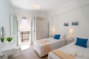 A hotel room with two beds, a bathroom, a balcony, and a view of the sea.
