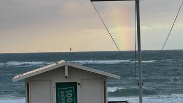 A beachside building with a green sign, a wooden deck, and a view of the ocean.