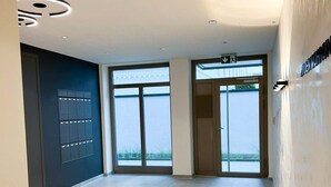 A spacious, modern interior with large windows, a tiled floor, and a wall-mounted control panel. - Anchorage - Enjoy your vacation close to the beach and the city center (Sylt)
