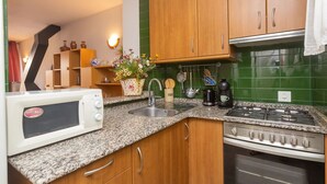 Une cuisine avec des meubles en bois, un plan de travail en granit, un four à micro-ondes, un évier, une cuisinière et une machine à café.