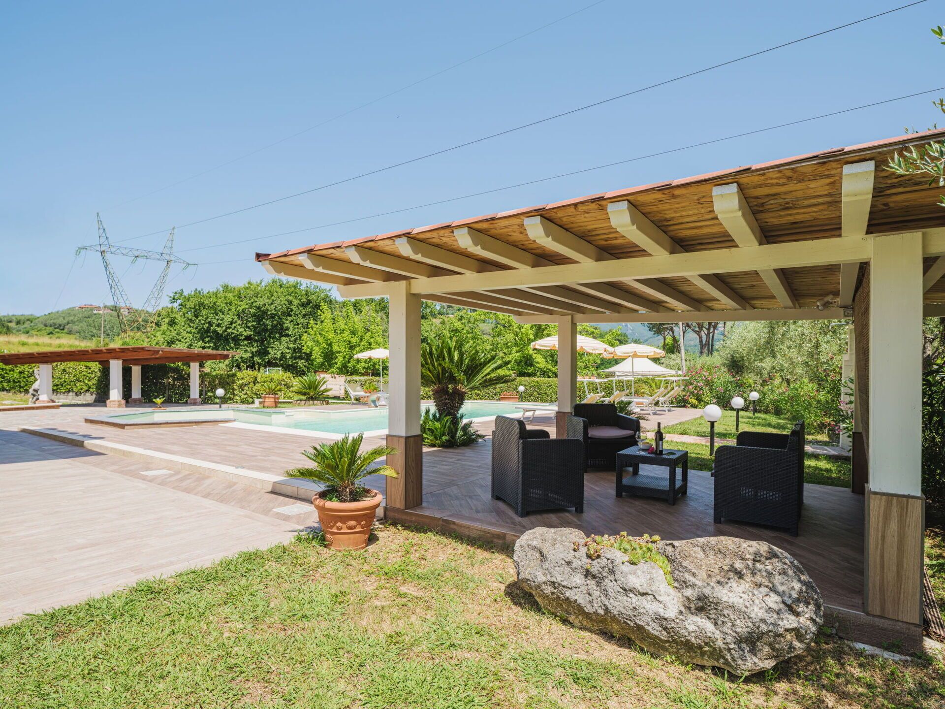 A covered outdoor area with a pool, lounge chairs, and a pergola.