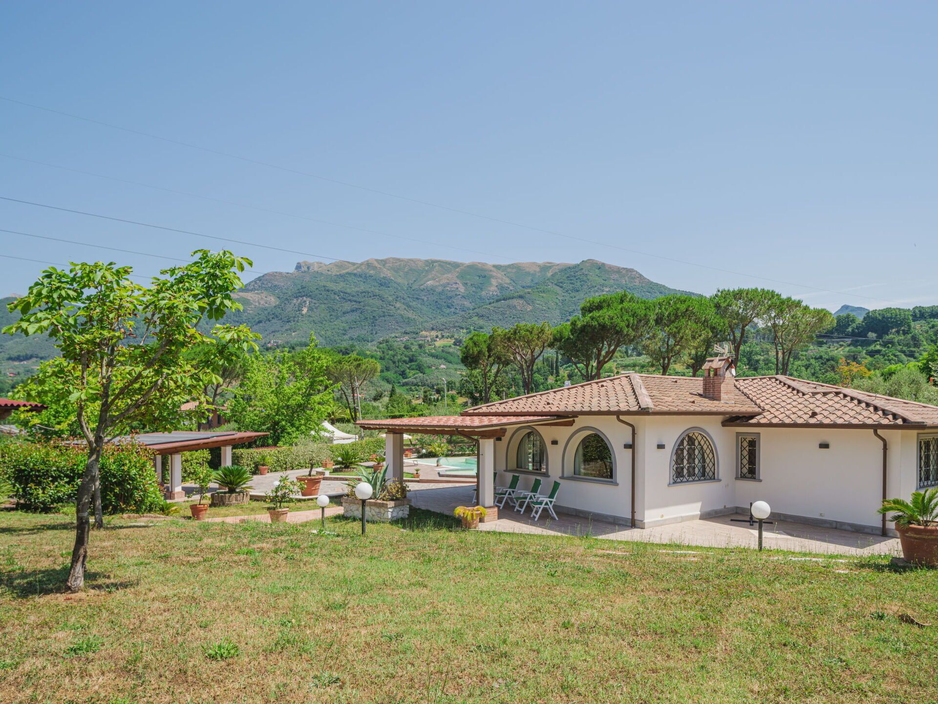 A villa with a tiled roof, a swimming pool, and a view of mountains.