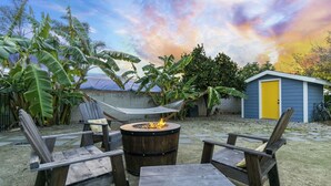 A backyard with a fire pit, wooden chairs, and a hammock. - Mile to Ocean! Fully Fenced Private SoCal Cottage (Oceanside)