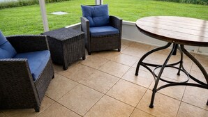 A patio area with wicker furniture and a round table. - Remodeled 2BR Near Gulf Beaches Fast Wi-Fi (Holiday)