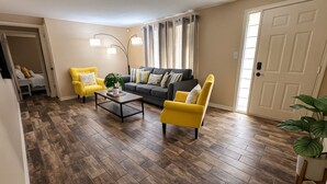 A living room with a sofa, two yellow armchairs, a coffee table, and a plant. - Remodeled 2BR Near Gulf Beaches Fast Wi-Fi (Holiday)