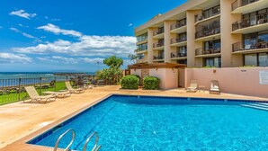 A swimming pool with lounge chairs, a view of the ocean, and a multi-story building with balconies. - Ma'alaea studio just a few steps from the ocean, beach, and harbor. (Wailuku)