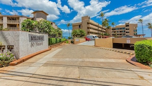 A hotel entrance with a clear sky, palm trees, and a parking area. - Ma'alaea studio just a few steps from the ocean, beach, and harbor. (Wailuku)