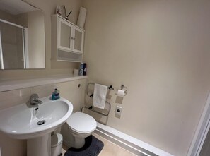 A bathroom with a white sink, toilet, and a mirror above the sink. There are toiletries on the shelf above the mirror. - Aberdeen Stay Central 2-bedrooms Apt-no Party (Aberdeen)