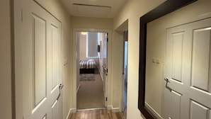 A hallway with a carpeted floor leading to a bedroom with a bed and a window. - Aberdeen Stay Central 2-bedrooms Apt-no Party (Aberdeen)