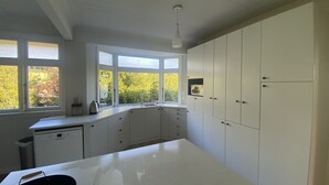 A modern kitchen with white cabinetry, a large window, and a countertop. - Amazing views! 5 mins to beach (Dunedin)